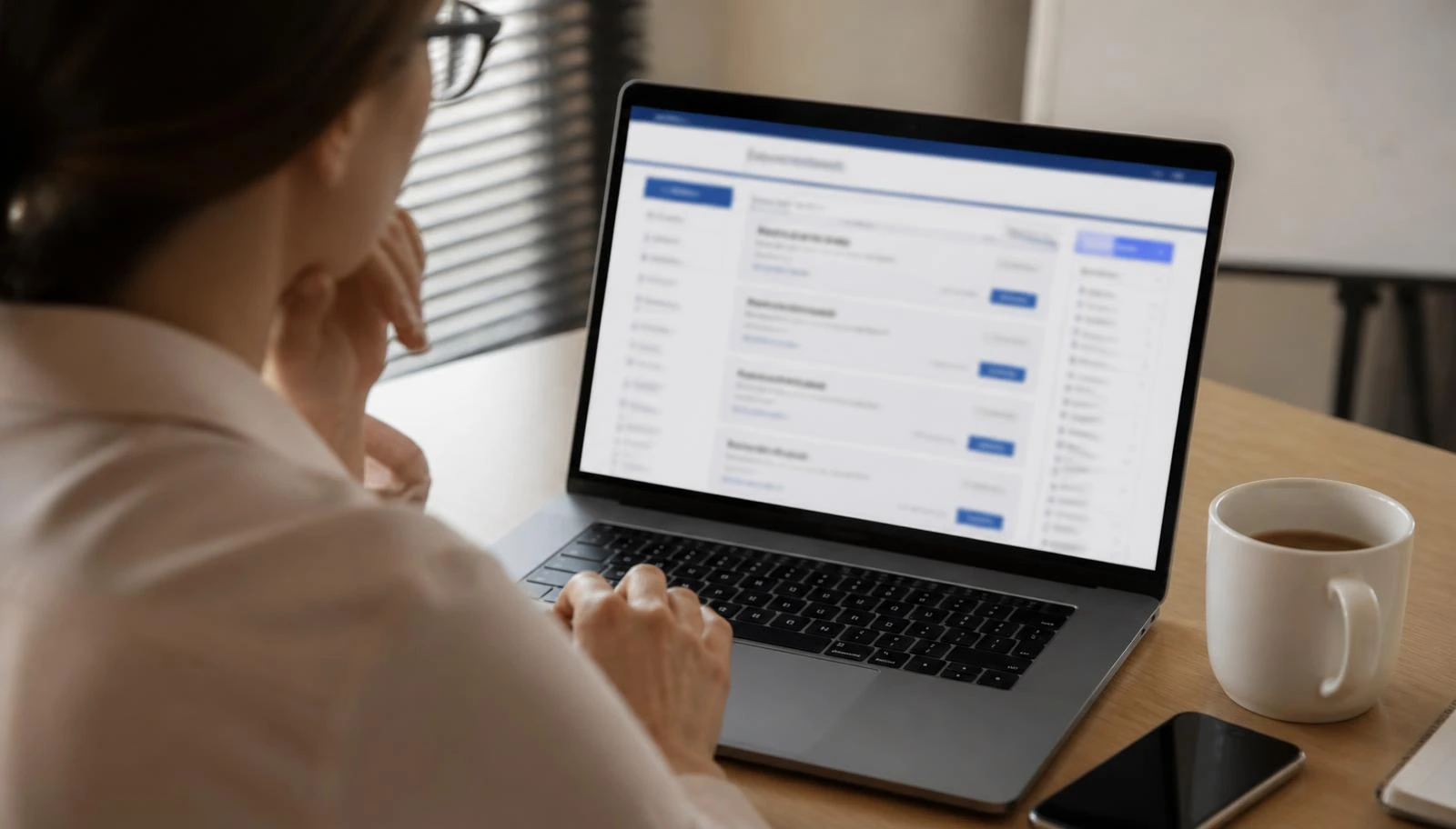 Pessoa pesquisando anúncios de vagas de emprego em um notebook sobre mesa de escritório